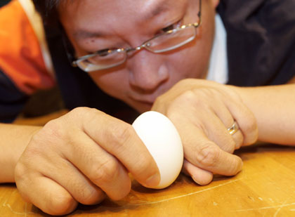 Taiwaneses try to stand an egg stand during the annual Dragon Boat Festival in Taipei May 31, 2006. Egg-standing at noon is a custom that takes place during the Dragon Boat Festival, commemorated in memory of the drowned poet Qu Yuan.